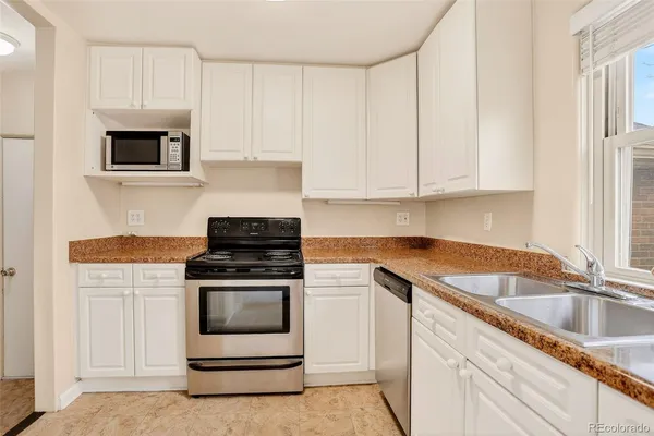 a kitchen with white cabinets and appliances