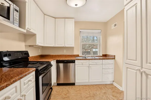a kitchen with granite countertop a stove a sink and a microwave