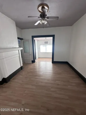 a view of empty room with wooden floor and ceiling fan