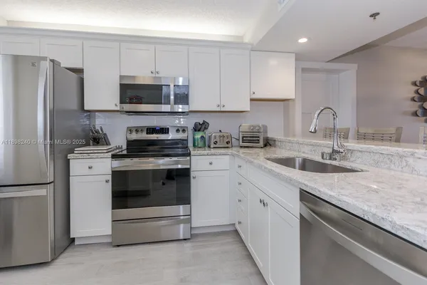 a kitchen with granite countertop white cabinets and stainless steel appliances
