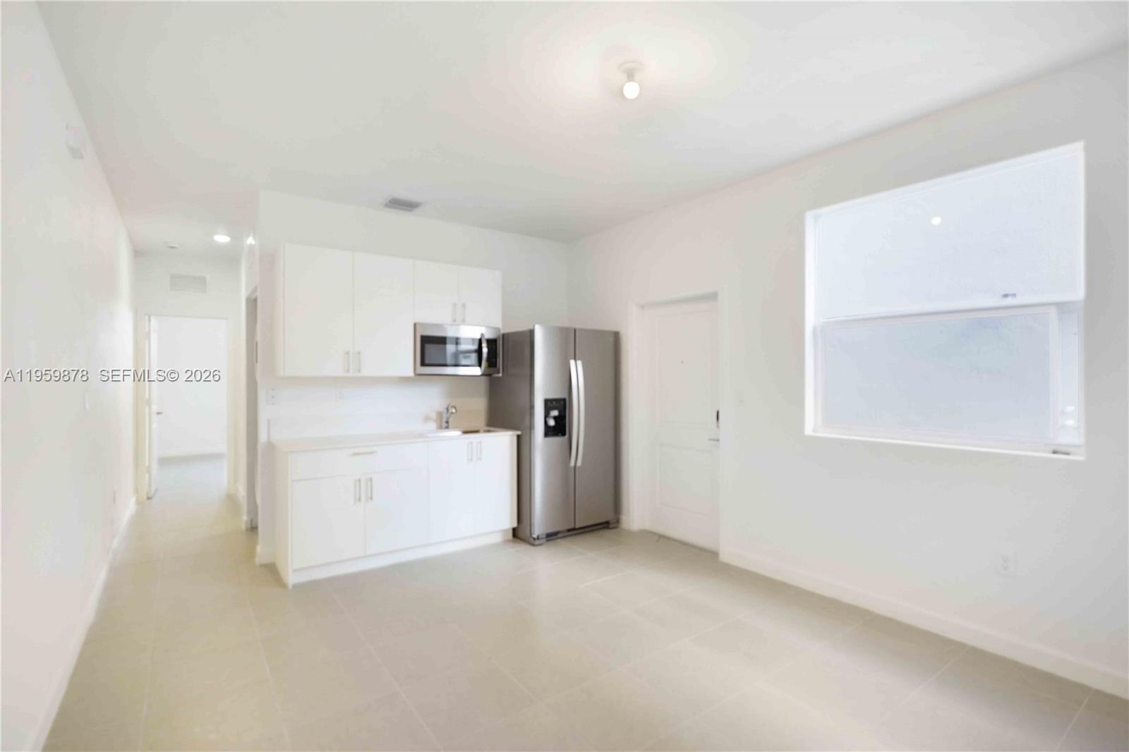 13621 Southwest 185th Lane, Unit A Miami, FL 33177 - Photo 3 of 9 a view of a kitchen with a refrigerator white cabinets and a refrigerator