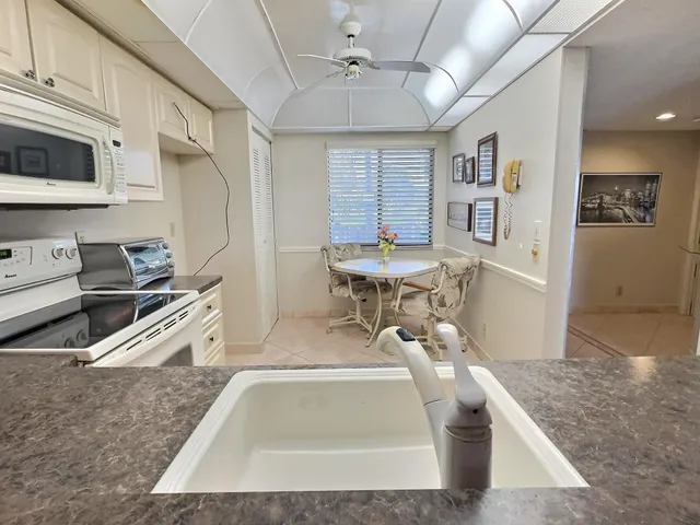 a view of a kitchen with stainless steel appliances granite countertop a sink dishwasher a stove top oven a dining table and chairs with wooden floor