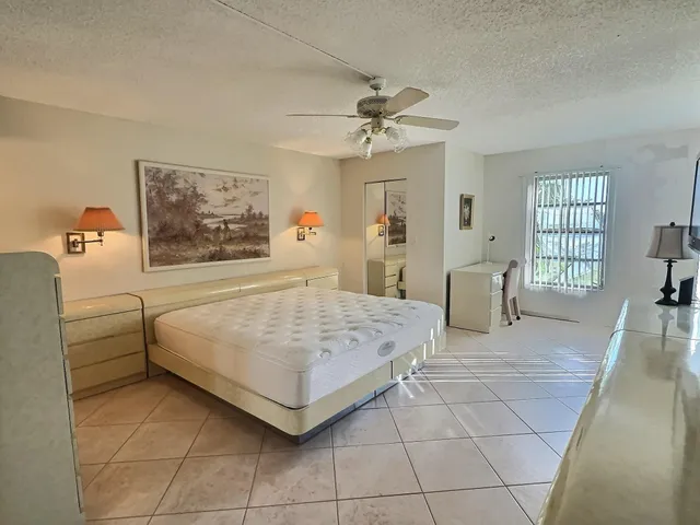 a spacious bedroom with a bed a dresser and a window