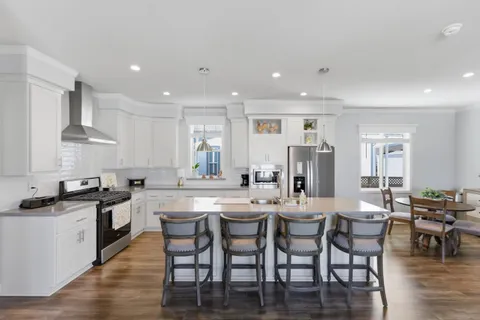 a kitchen with stainless steel appliances granite countertop a stove a sink a dining table and chairs
