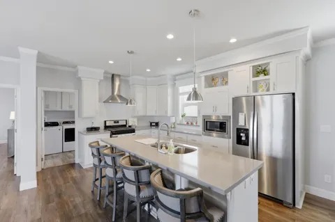 a kitchen with a dining table chairs refrigerator and microwave