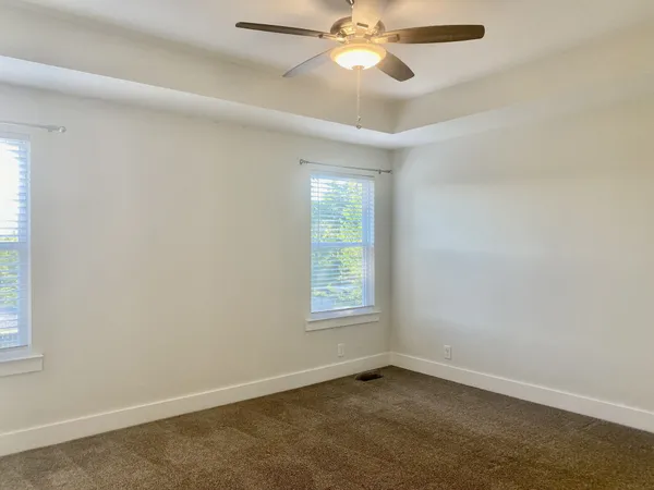 an empty room with windows and fan