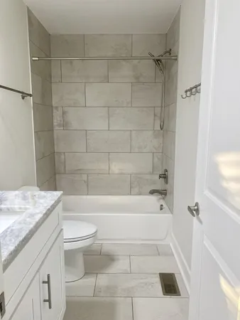 a bathroom with a granite countertop bathtub shower sink vanity and toilet