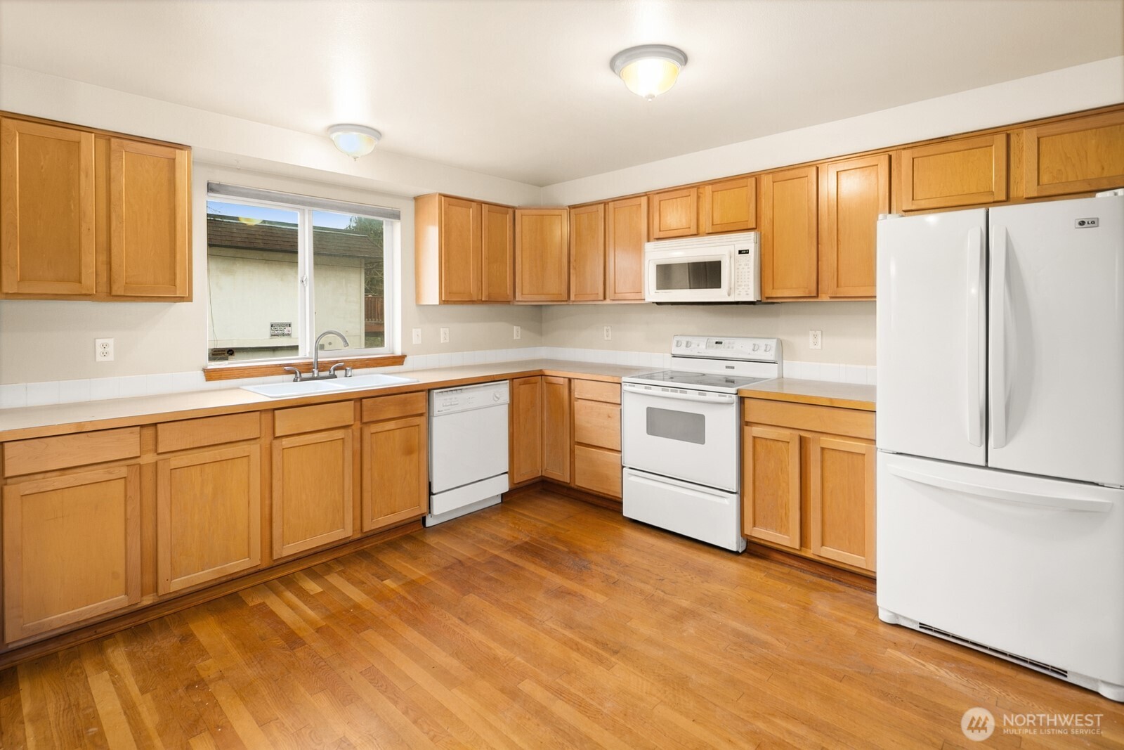 1417 North 97th Street Seattle, WA 98103 - Photo 7 of 23 a kitchen with a sink cabinets stainless steel appliances and a window