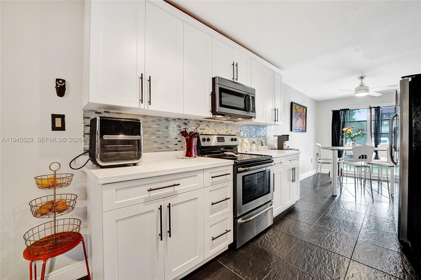 3301 Raleigh Street, Unit 4E Hollywood, FL 33021 - Photo 20 of 80 a kitchen with stainless steel appliances granite countertop a stove top oven a sink dishwasher and white cabinets with wooden floor