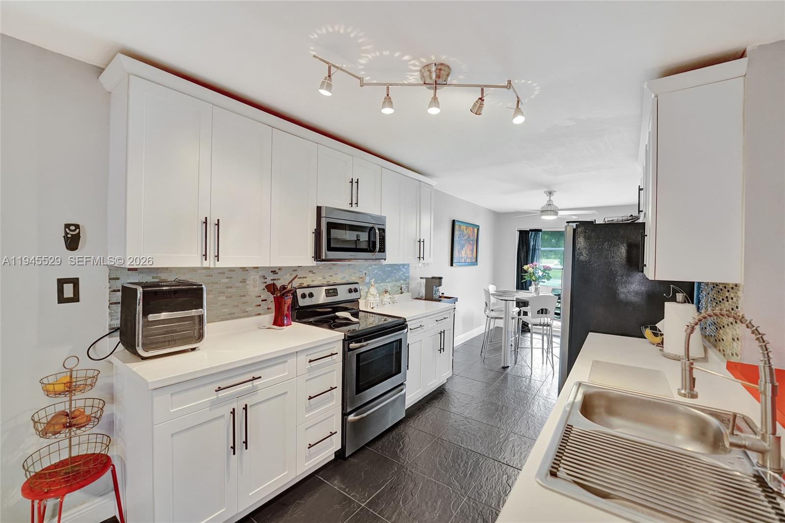 3301 Raleigh Street, Unit 4E Hollywood, FL 33021 - Photo 2 of 80 a kitchen with stainless steel appliances kitchen island granite countertop a stove top oven a sink a dining table and chairs with white cabinets