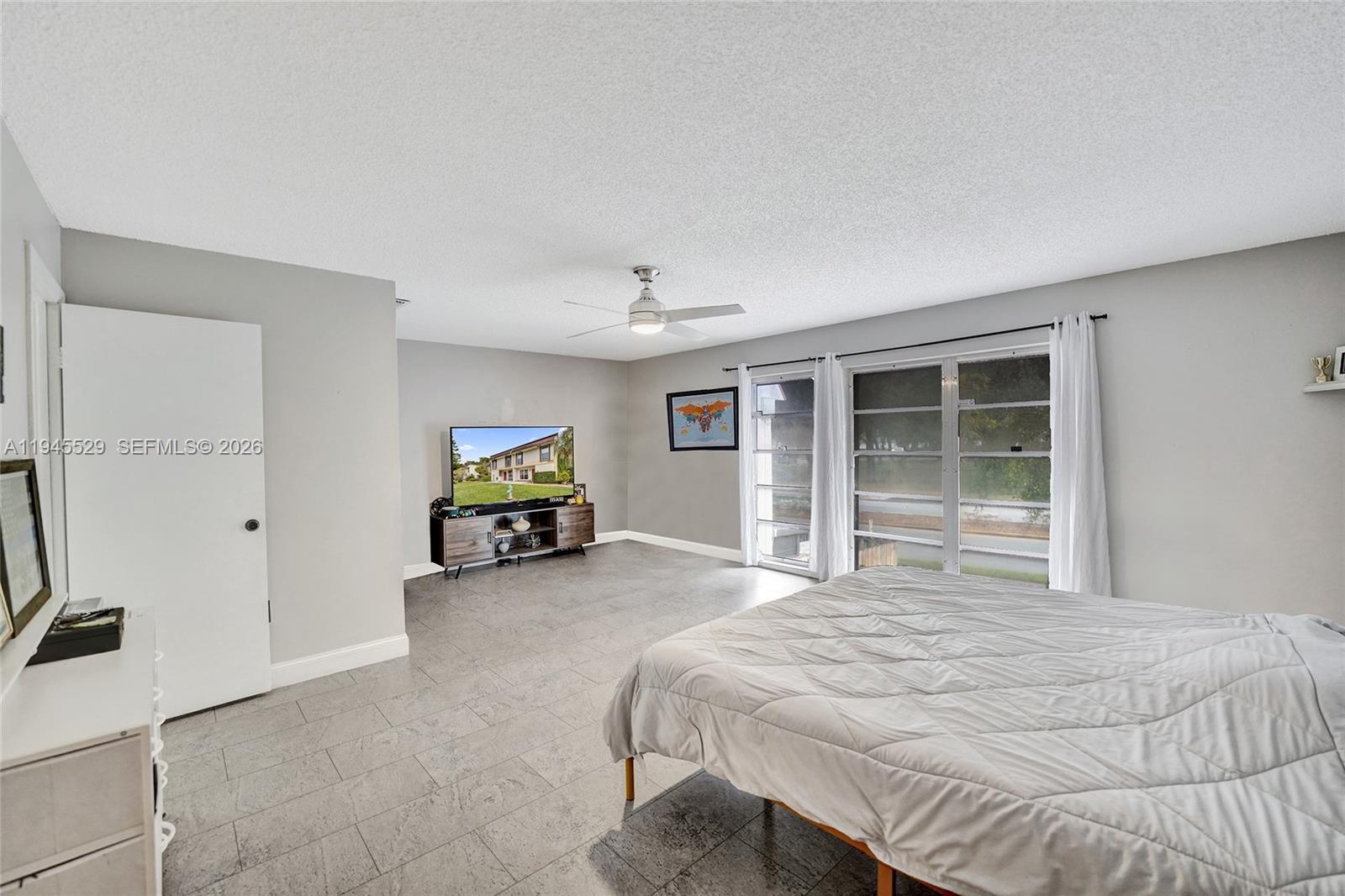 3301 Raleigh Street, Unit 4E Hollywood, FL 33021 - Photo 61 of 80 a bed sitting in a spacious bedroom next to a window and a flat screen tv
