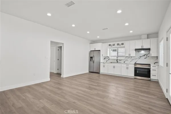 a view of a kitchen with a sink and dishwasher a refrigerator with wooden floor