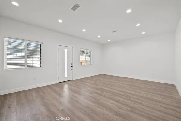 an empty room with wooden floor and windows
