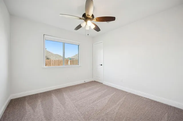 an empty room with a window and a fan