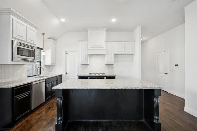 a kitchen with stainless steel appliances granite countertop a sink a stove a refrigerator and cabinets