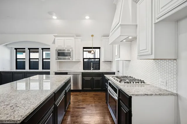 a kitchen with granite countertop kitchen island stainless steel appliances a sink stove and cabinets
