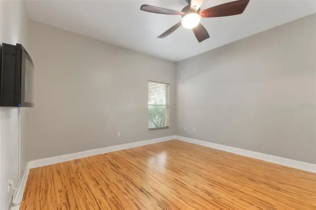 an empty room with wooden floor fan and windows