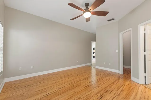 an empty room with wooden floor and a ceiling fan
