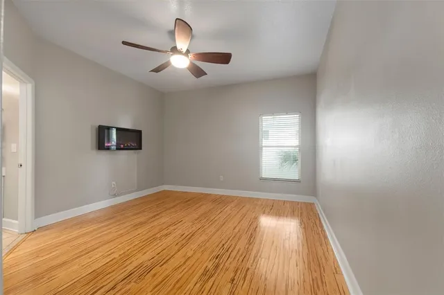 a view of empty room with wooden floor and fan