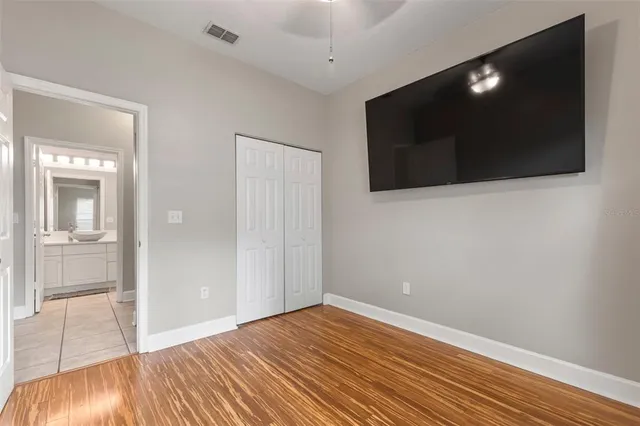 a view of empty room with wooden floor and fan