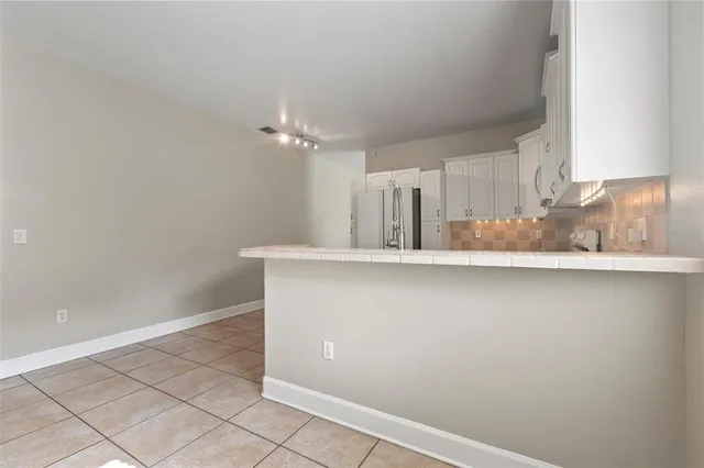 an empty room with kitchen view and natural light