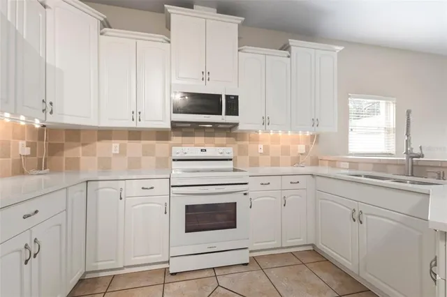a kitchen with white cabinets appliances and a window