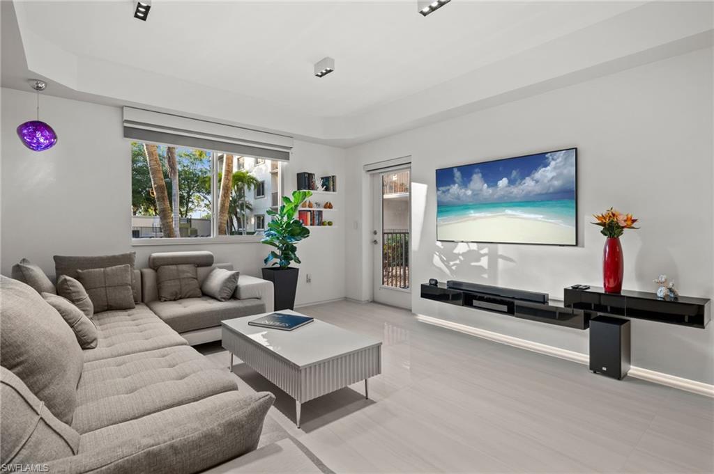 1100 Pine Ridge Road, Unit B103 Naples, FL 34108 - Photo 14 of 38 a living room with furniture a flat screen tv and a large window