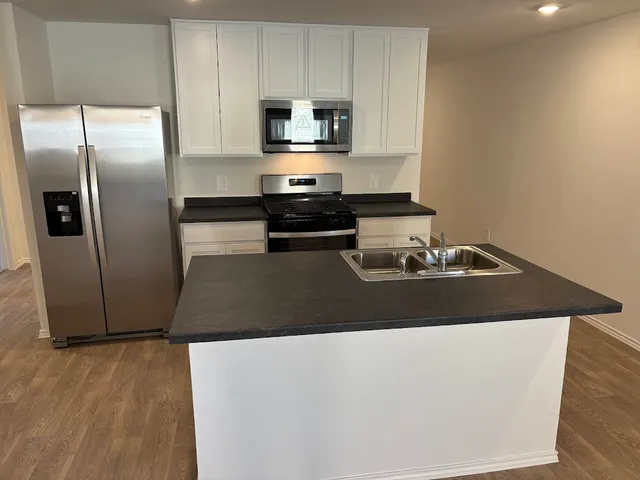 a kitchen with granite countertop a refrigerator and a stove top oven