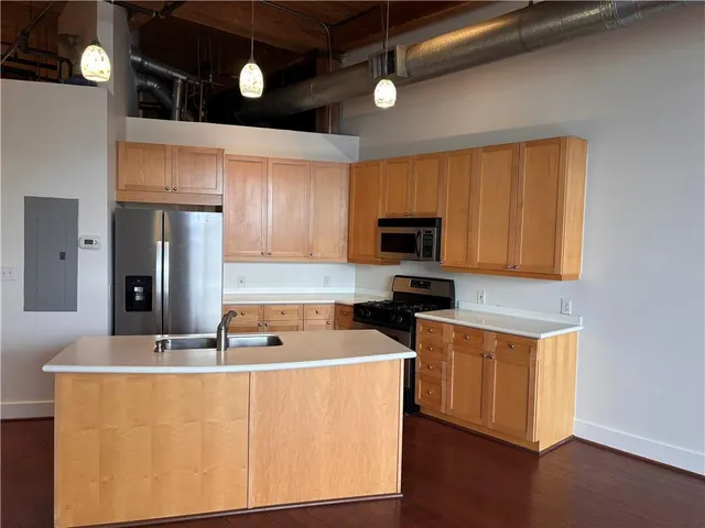 a kitchen with stainless steel appliances a stove a refrigerator a sink cabinets and wooden floor