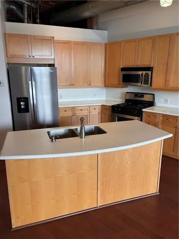 a kitchen with stainless steel appliances a refrigerator a sink a stove a microwave and wooden cabinets