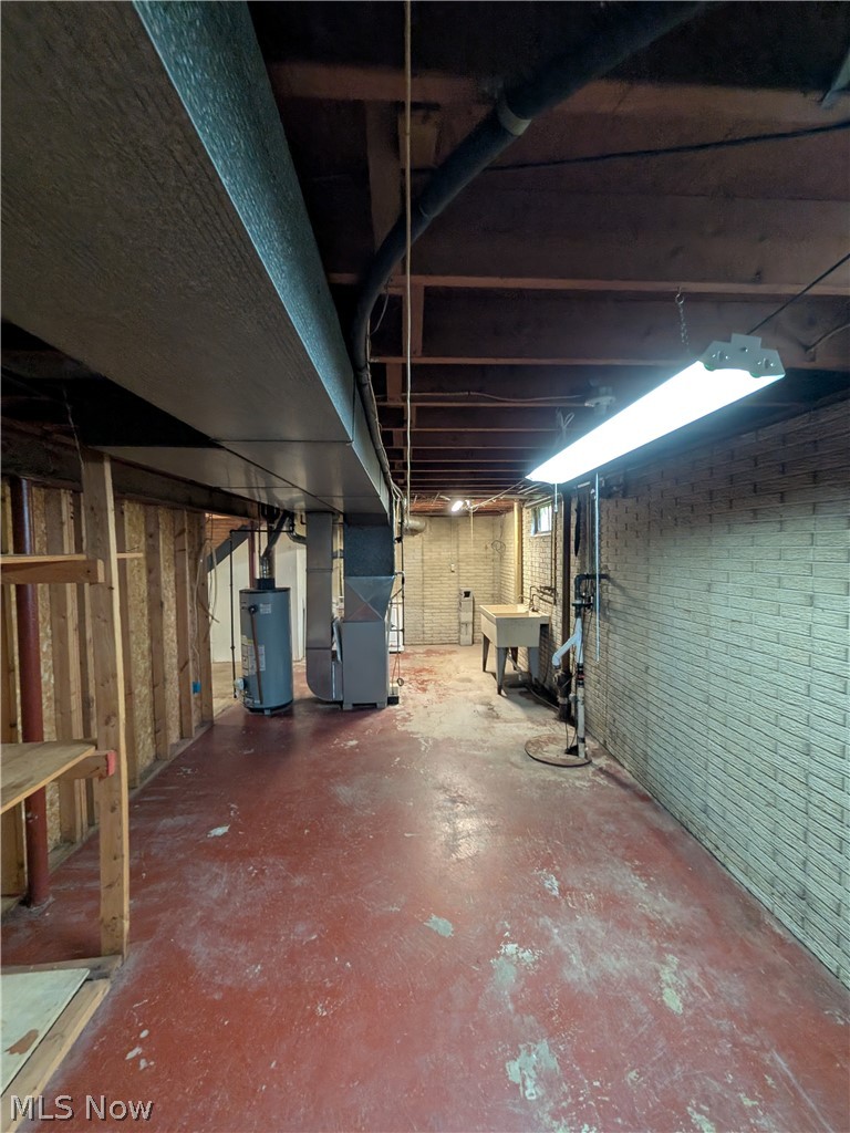 1161 Gulf Road Elyria, OH 44035 - Photo 31 of 34 Expansive utility space featuring a red-painted concrete floor, exposed ceiling joists, and brick-patterned wall