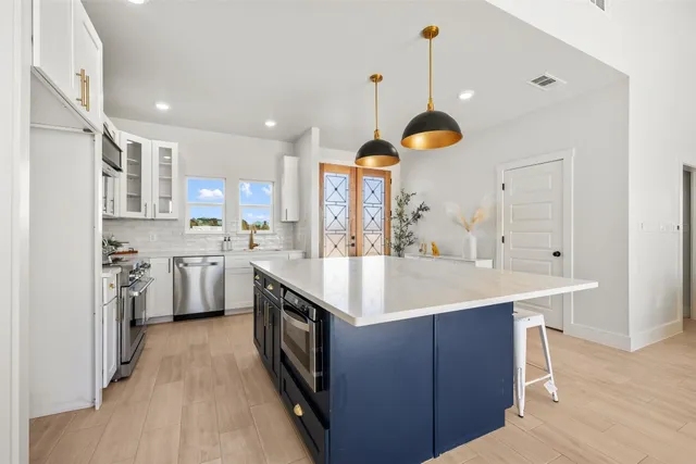 a large kitchen with stainless steel appliances granite countertop a sink and a wooden floors