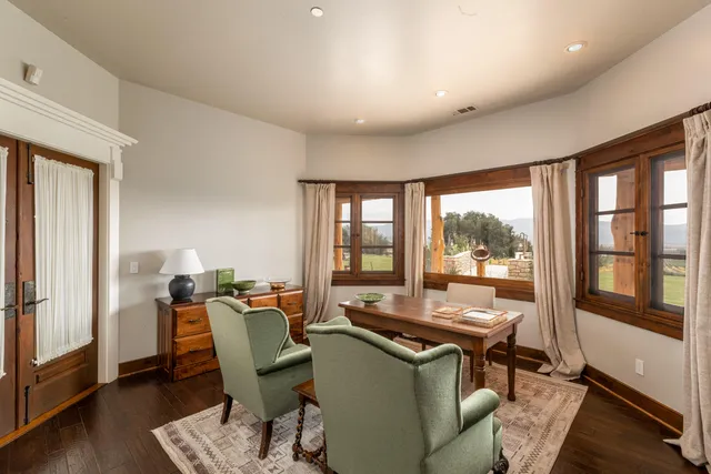 a dining room with furniture and large windows