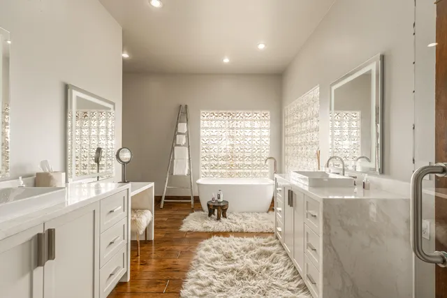 a spacious bathroom with double vanity a window a mirror a bathtub and shower