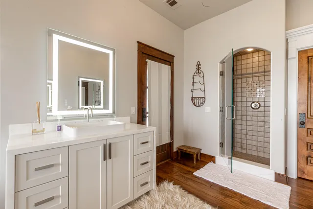 a spacious bathroom with a double vanity sink a mirror and shower