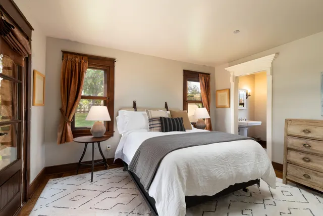 a bedroom with a bed and large windows