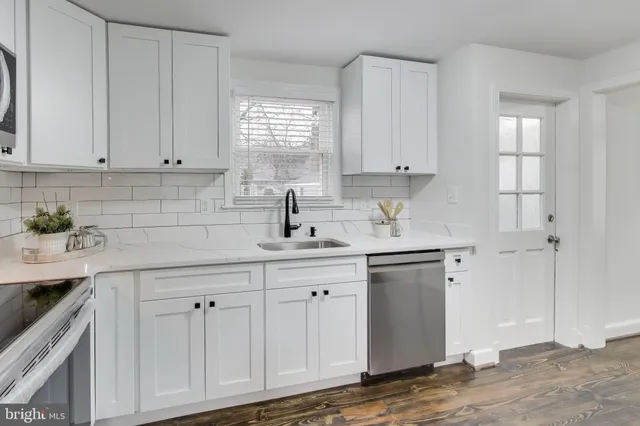 a kitchen with white cabinets and sink