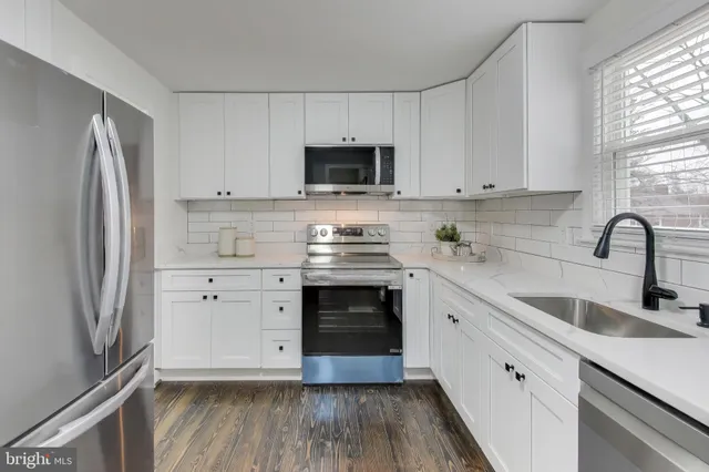 a kitchen with white cabinets stainless steel appliances and a window