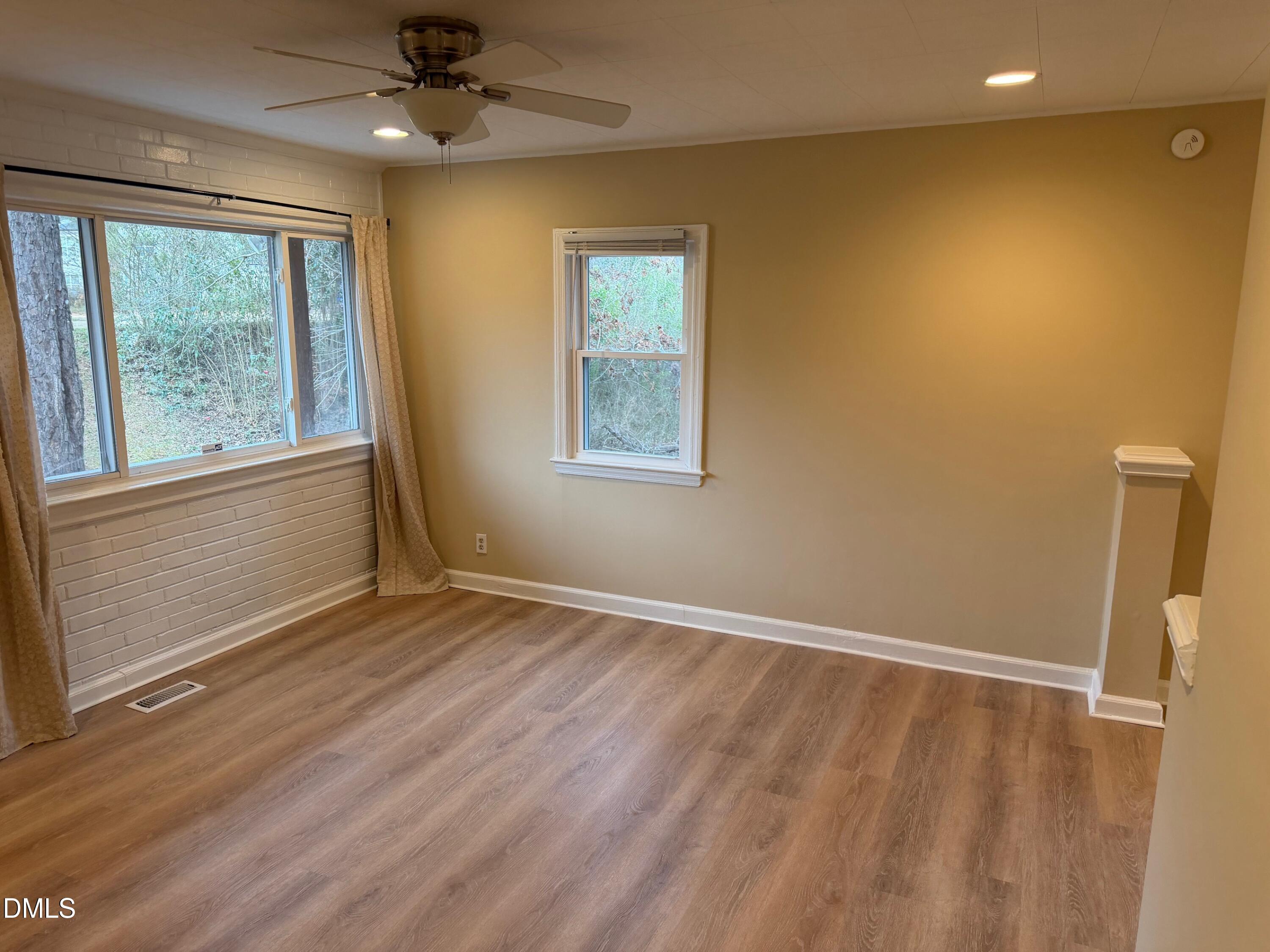 3117 Tryon Road Raleigh, NC 27603 - Photo 8 of 21 a view of an empty room with a window and wooden floor