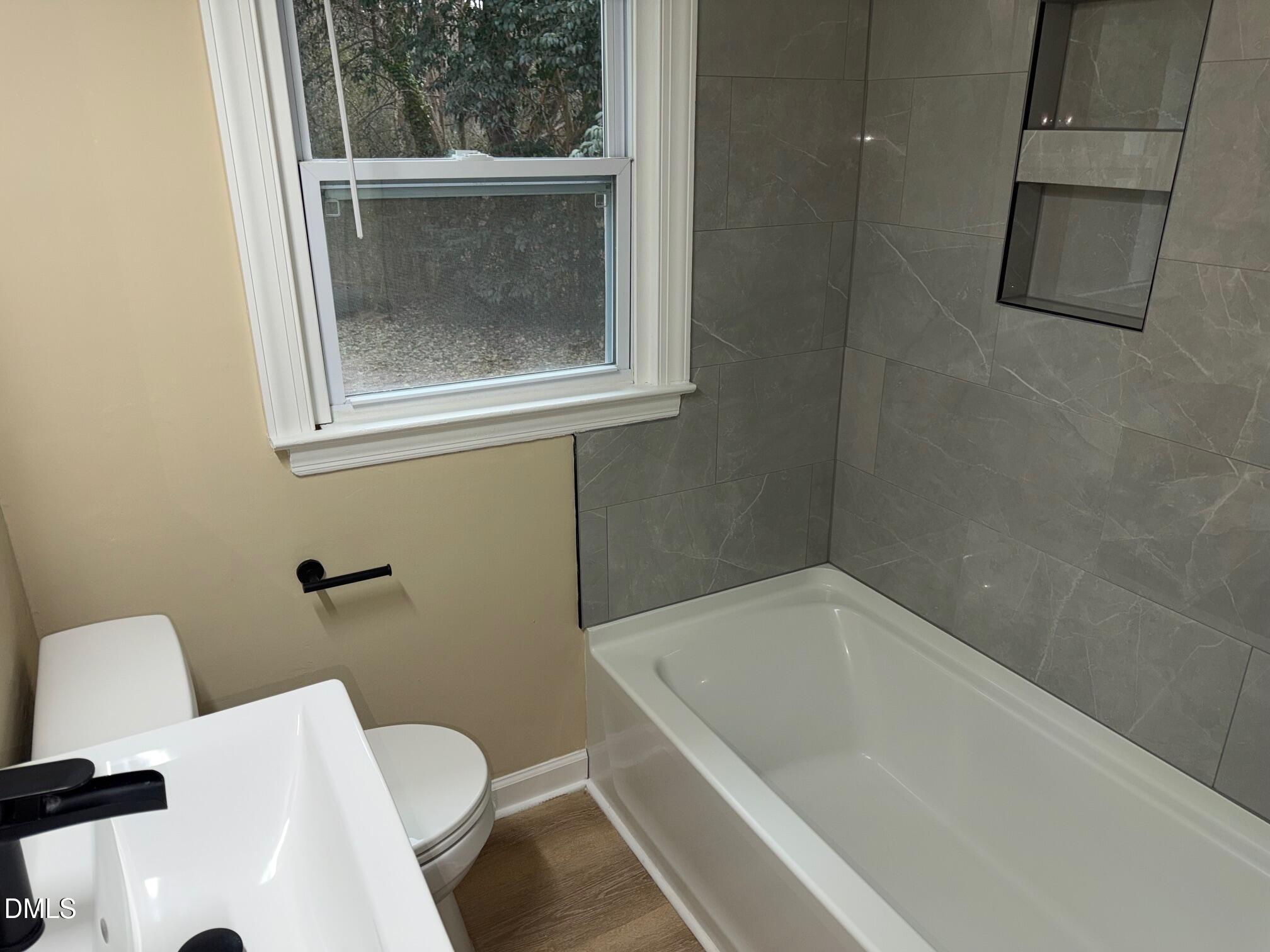 3117 Tryon Road Raleigh, NC 27603 - Photo 9 of 21 a bath tub sitting next to a white toilet and a window