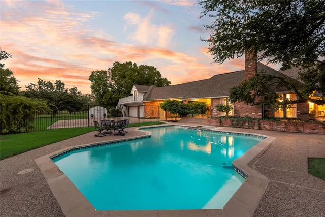 a view of a swimming pool with lawn chairs under an umbrella