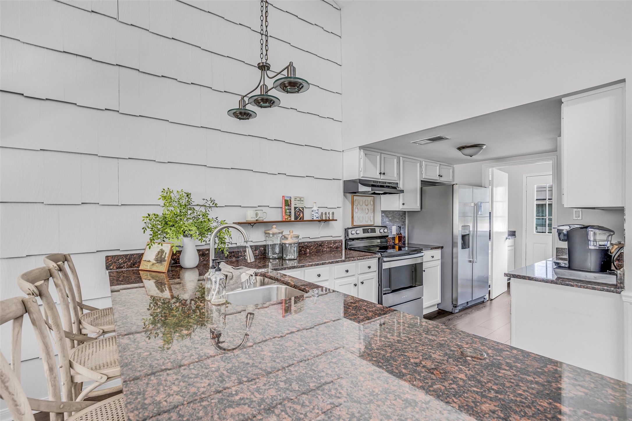62 April Point Drive North Conroe, TX 77356 - Photo 18 of 25 a kitchen with stainless steel appliances kitchen island granite countertop a refrigerator a stove a sink dishwasher and white cabinets with wooden floor