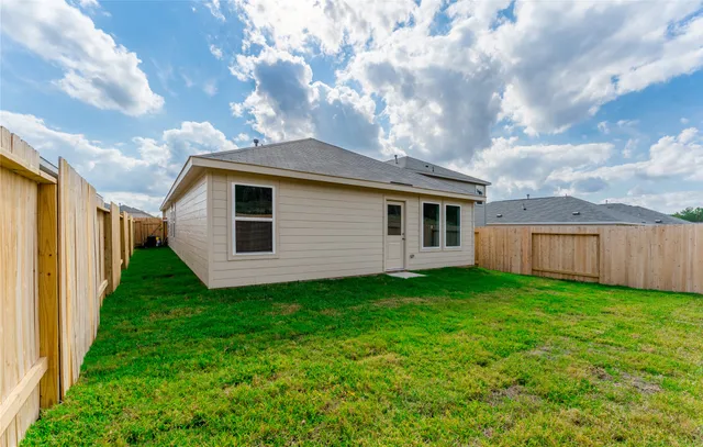 a view of backyard of house with wooden fence