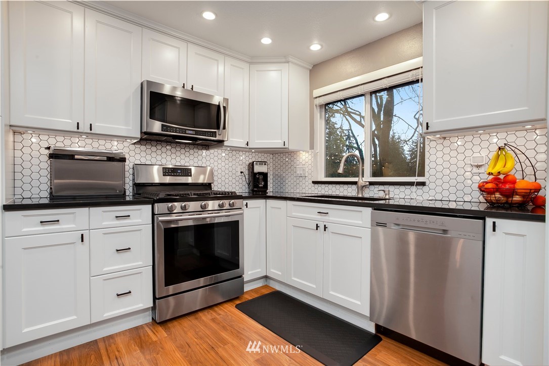 10727 126th Avenue Northeast Kirkland, WA 98033 - Photo 12 of 40 a kitchen with stainless steel appliances white cabinets a sink and a stove