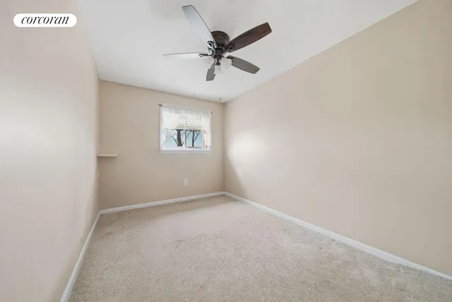 an empty room with a window and a ceiling fan