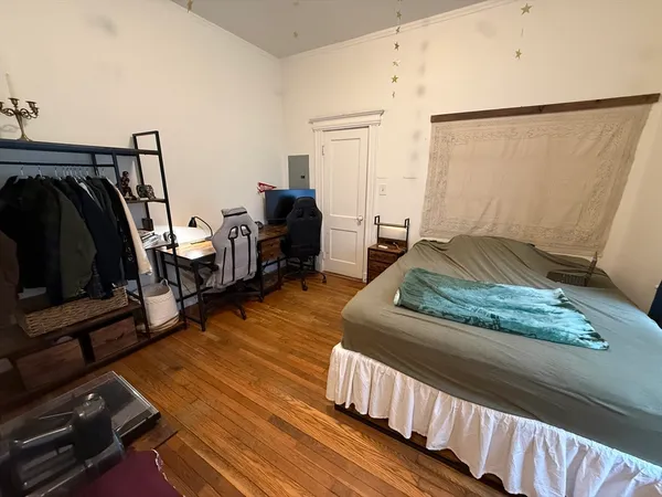 a bedroom with wooden floor and furniture