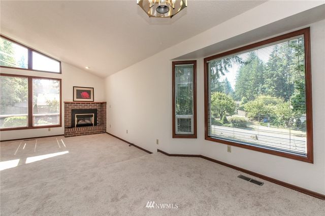 an empty room with windows a fireplace and a large window