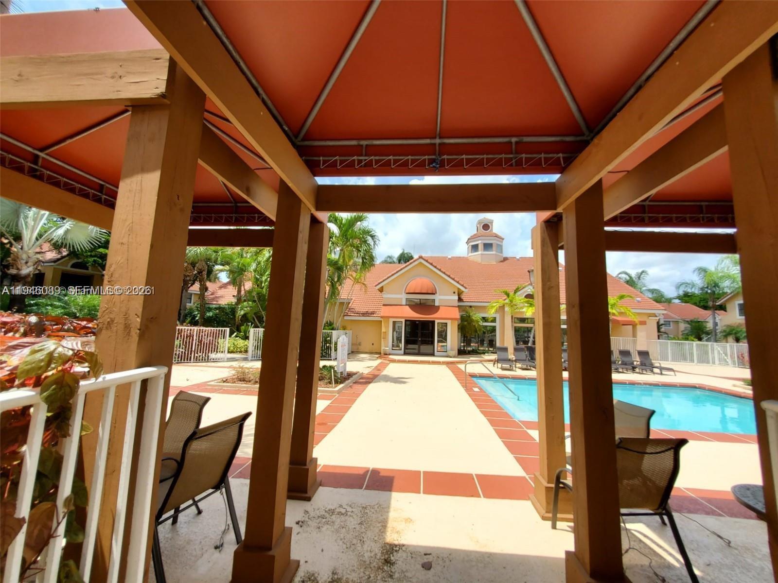 10500 Southwest 155th Court, Unit 1022 Miami, FL 33196 - Photo 40 of 41 a view of a patio with table and chairs under an umbrella