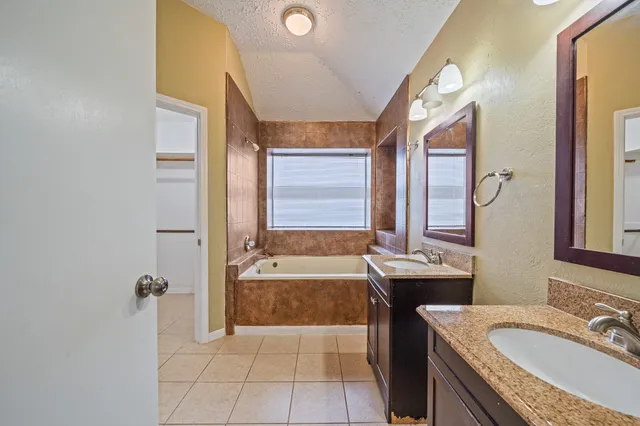 a bathroom with a granite countertop tub sink a mirror and a bathtub