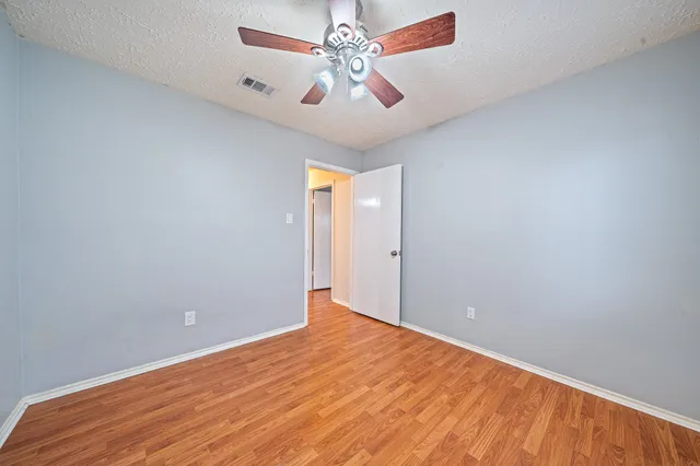 a view of an empty room with window and a ceiling fan